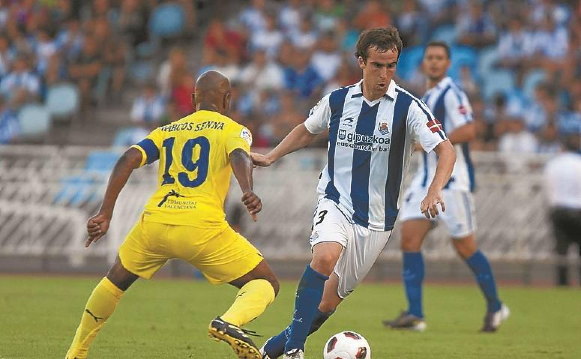 Mikel González conduce el balón ante Marcos Senna. 