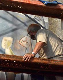 Imagen secundaria 2 - Arriba: Las humedades habían deteriorado parte de la pared del mural. A la izquierda: Xabier Egaña acometió la restauración de la pintura a finales del pasado mes. A la derecha: El artista durante los trabajos de recuperación de la pintura desde un andamio. 