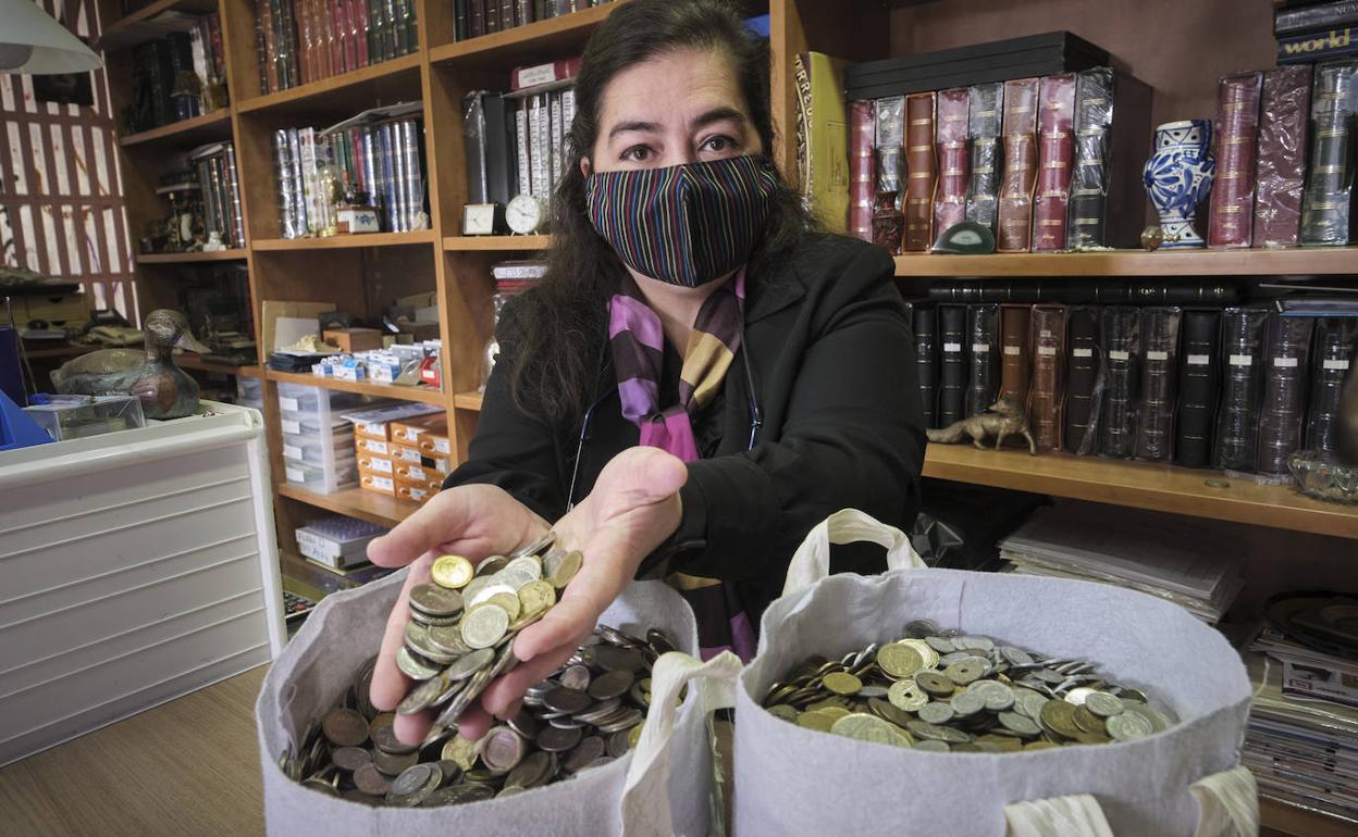 Canjeo de monedas. La numismática Esther Vívar muestra dos bolsas de pesestas en su establecimiento de Donostia. 