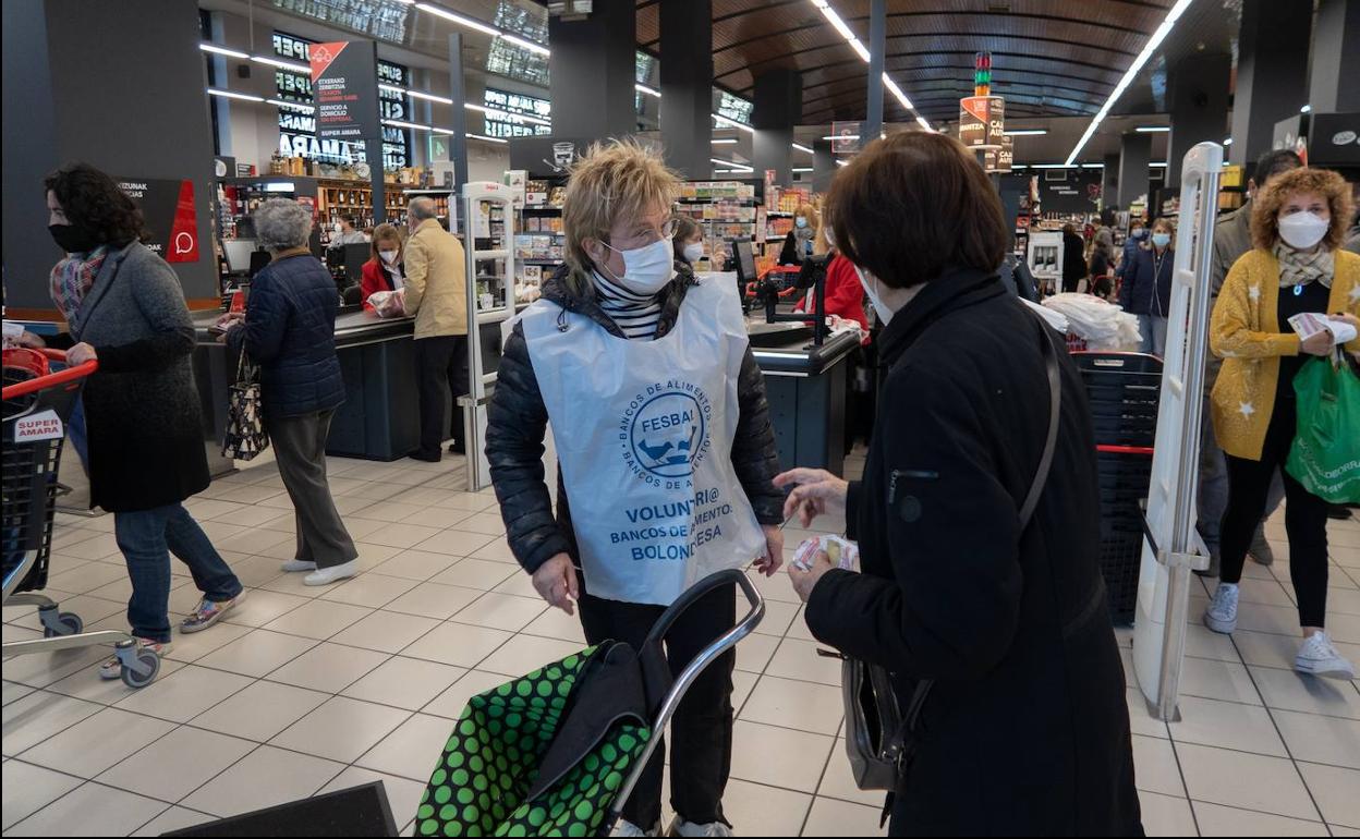 Una de las voluntarias del Banco de Alimentos explica a una mujer cómo participar..