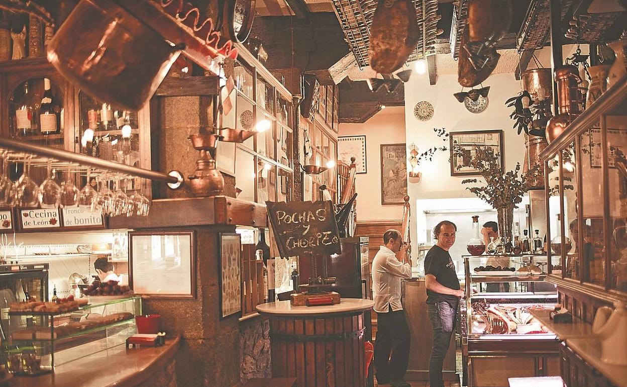 Interior de la Bodega Cigaleña, en Santander, y a la derecha, dos de sus variadas y ricas elaboraciones, almejas con arroz y steak tartar. 
