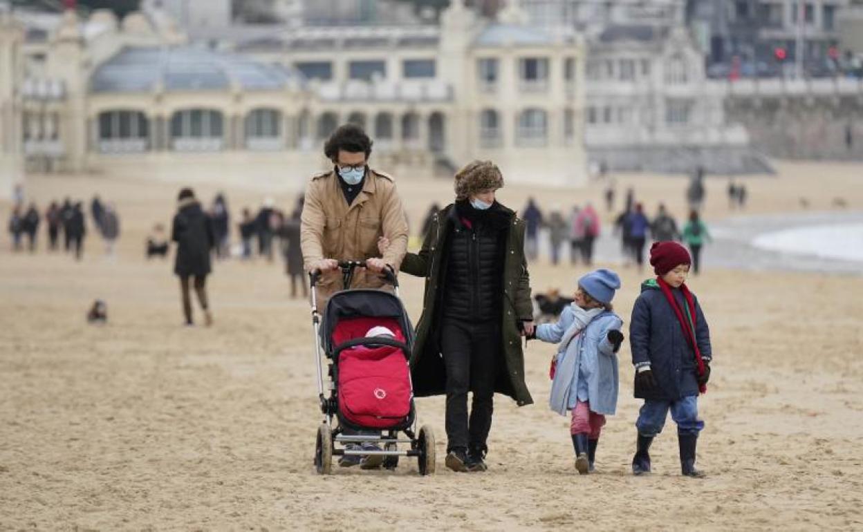 Una familia pasea por la platya de la Concha. 