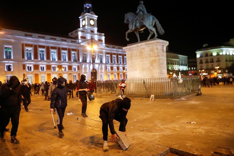 Varios manifestantes lanzan baldosas del suelo a las fuerzas de seguridad en la Puerta del Sol.