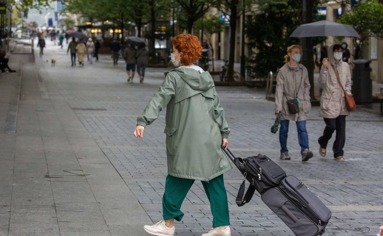 na mujer arrastra una maleta por una calle de San Sebastián. 