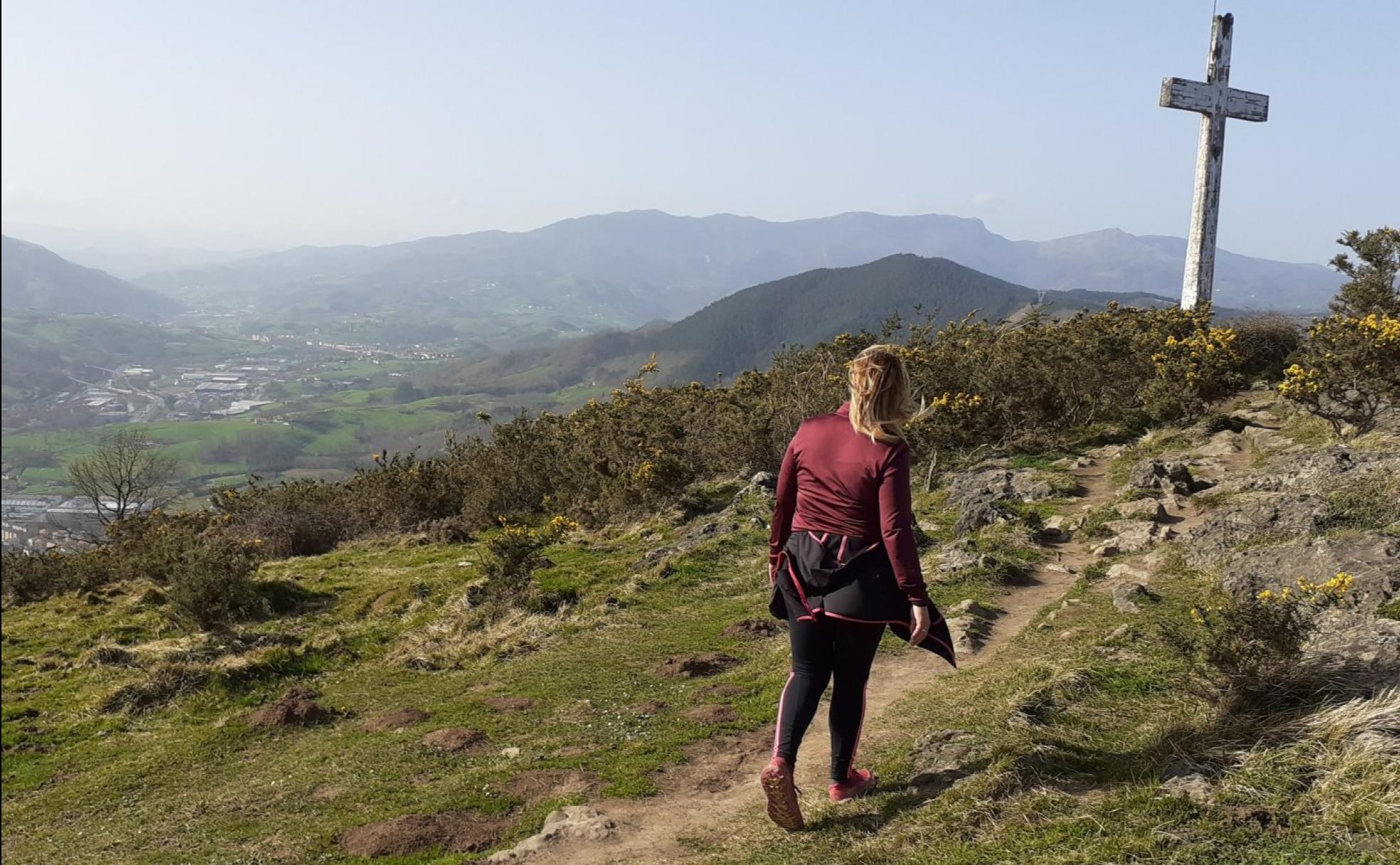 Una mendizale se dirige hacia la cruz que presideel monte y sitúa al Buruntza. 