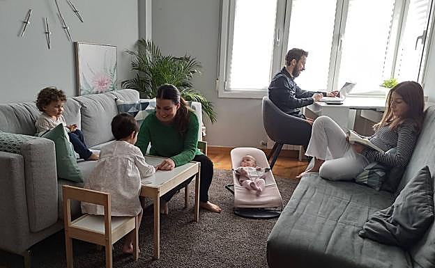 Marta y Patxi, en el salón de su casa mientras teletrabajan y entretienen a sus hijos.