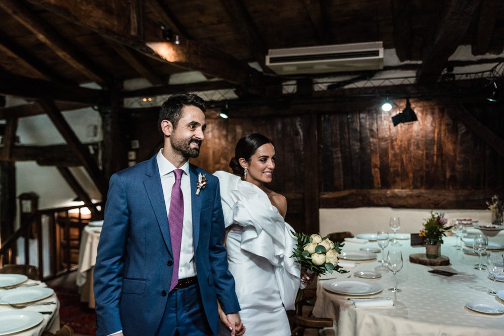 María y Jorge se casaron en Gorliz en una ceremonia íntima adaptada a las circunstancias. De largura 'mini' por encima de la rodilla, con corte asímetrico, volumen en la parte superior y lazadas laterales, la protagonista se ha convertido en una de las novias más impresionantes de las últimas semanas. El diseño lo ha firmado Fabio Encinar, uno de los diseñadores con sede en Madrid más de moda. En cuanto al peinado, otro de los elementos más destacados del estilismo, ha optado por un acertado moño bajo de bailarina súper pulido y tirante, con horquillas de Oui Novias