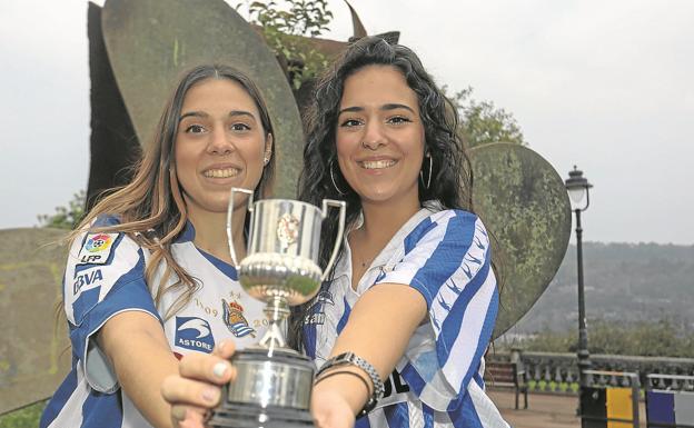 Naroa y June Dadíe posan en Pasaia con la réplica de la Copa ganada por su aita. June porta también una camiseta de Luis Fernando Dadíe.