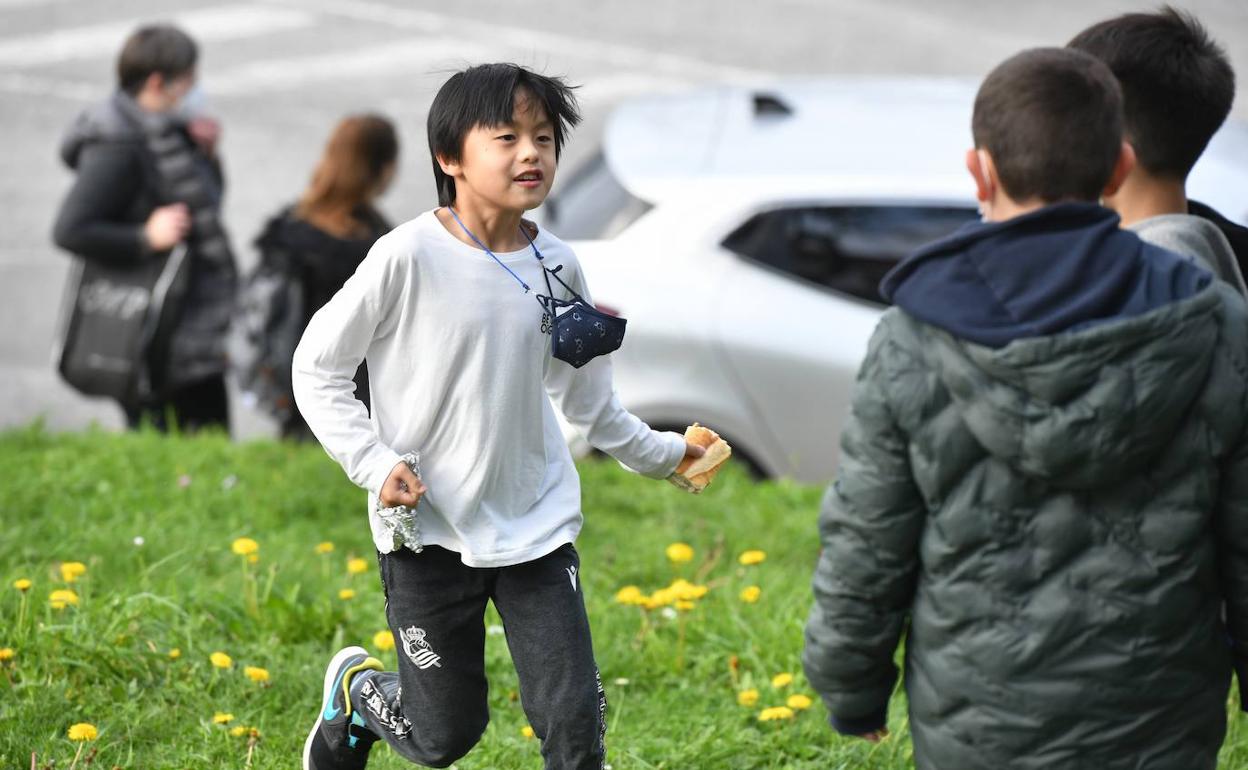 Xuan, con el bocadillo en la mano, juega con sus amigos después de salir de clase.