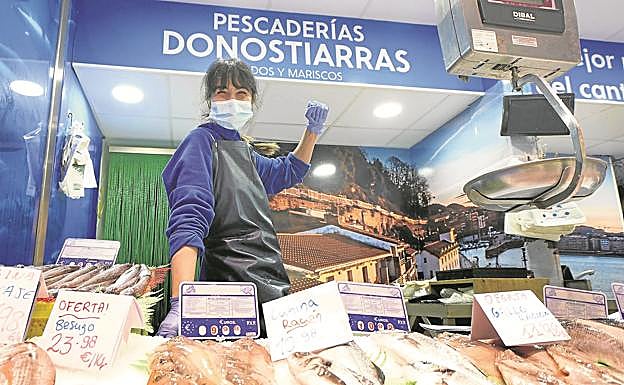 Cristina, de Pescaderías Donostiarras, ante un mural con una foto del muelle donostiarra.