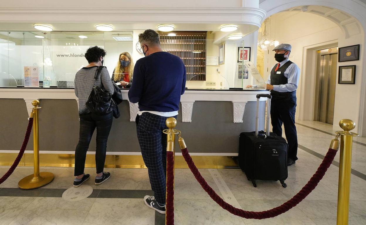 Una pareja de clientes completan el registro en la recepción del Hotel de Londres y de Inglaterra. 
