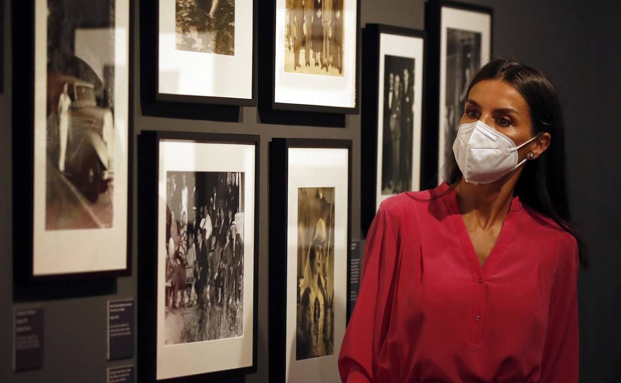 La reina Letizia observa algunas fotos de la exposición.
