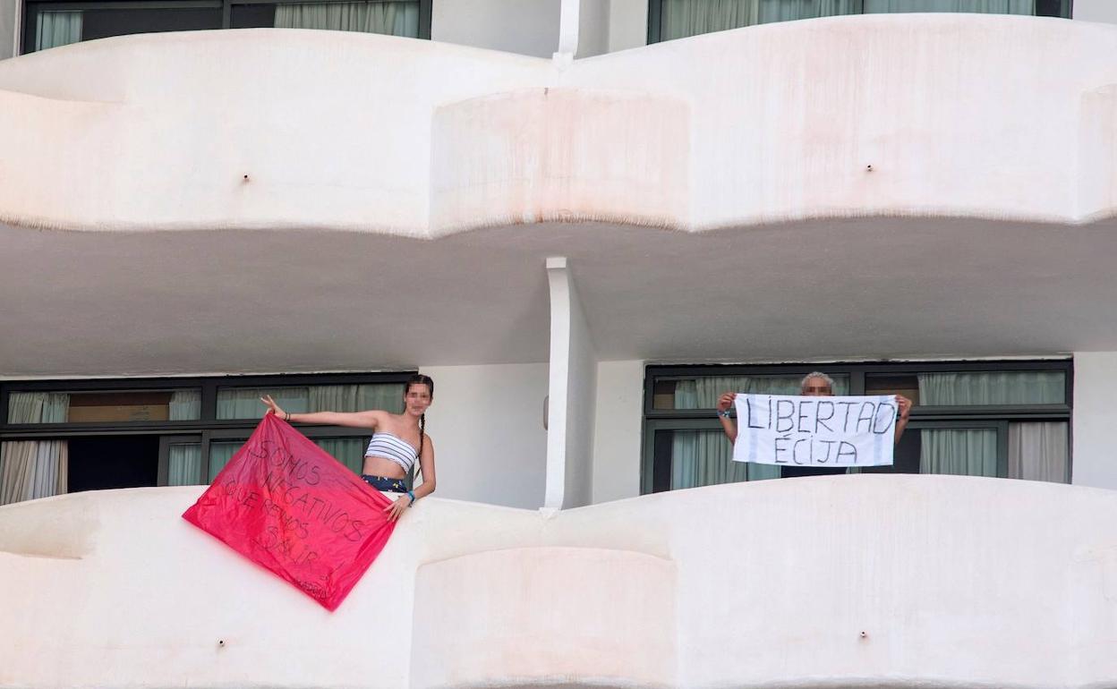 Dos jóvenes confinados en Mallorca muestran pancartas contra su aislamiento.