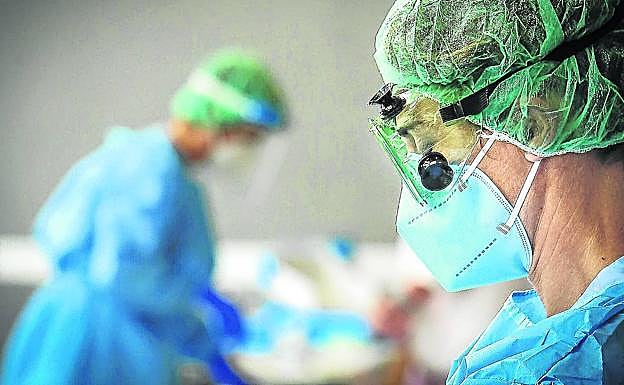 Dos sanitarios trabajando en un hospital con trajes de protección. 