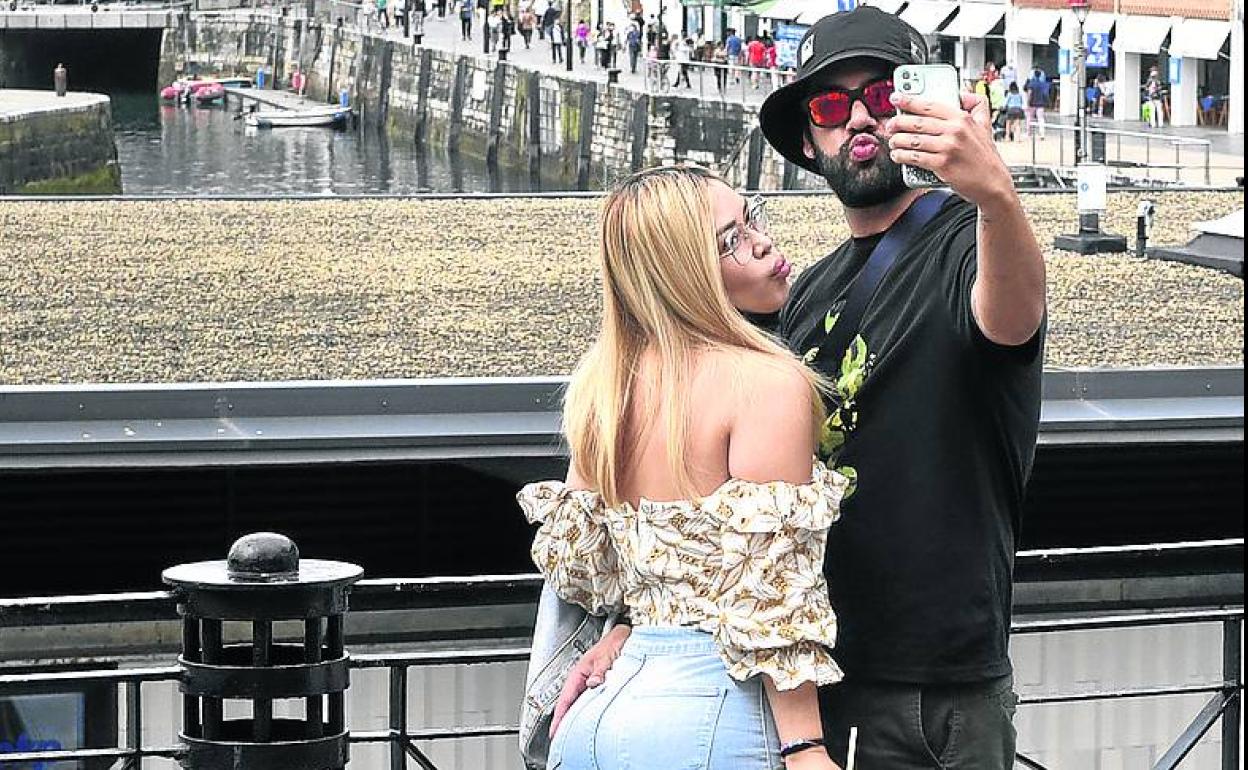 Una pareja se hace un selfi ante el muelle donostiarra.