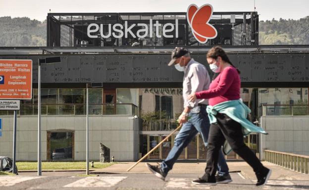 Dos personas pasean frente a la sede central del Grupo Euskaltel, en el parque tecnológico de Zamudio.