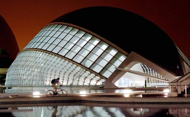 Un ciclista pasa por delante del edificio del Hemisferic de la Ciudad de las Artes y las Ciencias de Valencia.