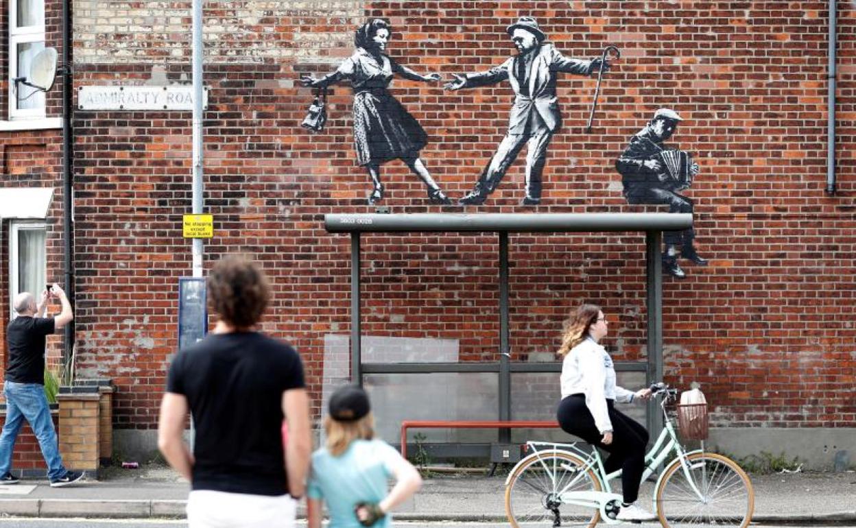 Una pareja baila y un hombre toca el acordeón en una de las nuevas obras del artista callejero. 