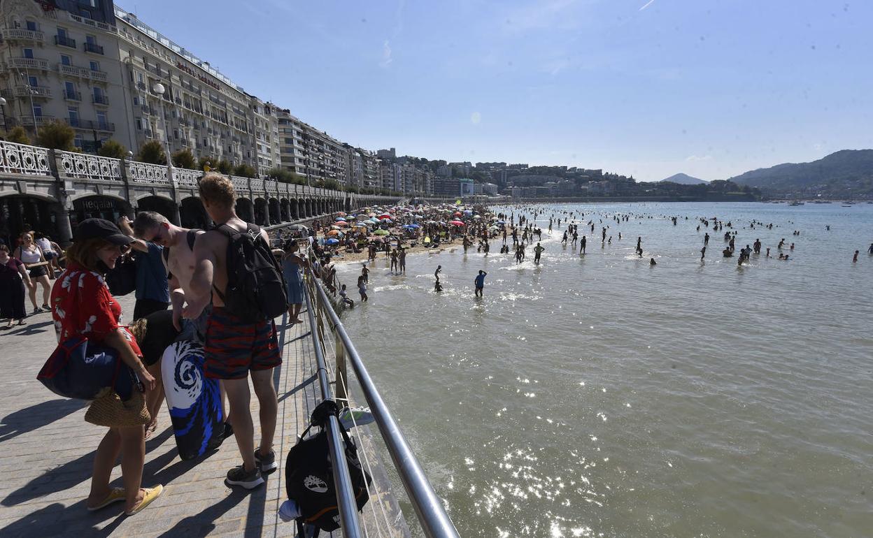 Varios grupos hacen cola a la entrada de la playa de La Concha en pleamar.