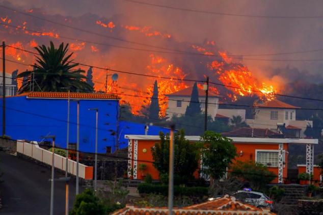 La lava fluye detrás de las casas tras la erupción del volcán.