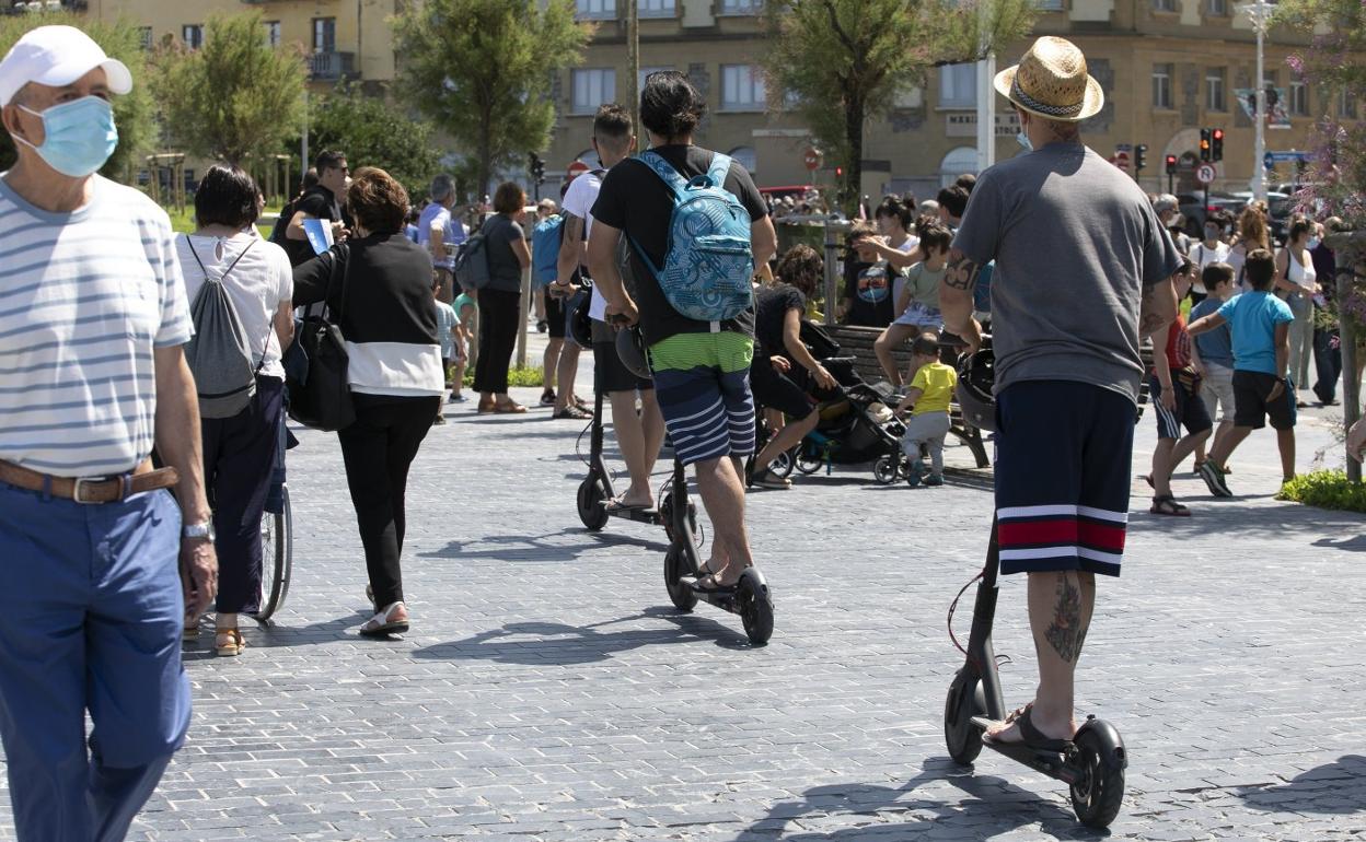 Varias personas circulan con patinete eléctrico por el paseo de la Zurriola. 