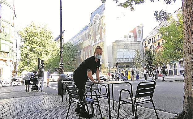 Alexandra Cavanna limpia una mesa de la terraza de su cafetería Txris, al final de la calle Urbieta, desde donde se contempla, como en ningún otro sitio, el degradado edificio Bellas Artes.