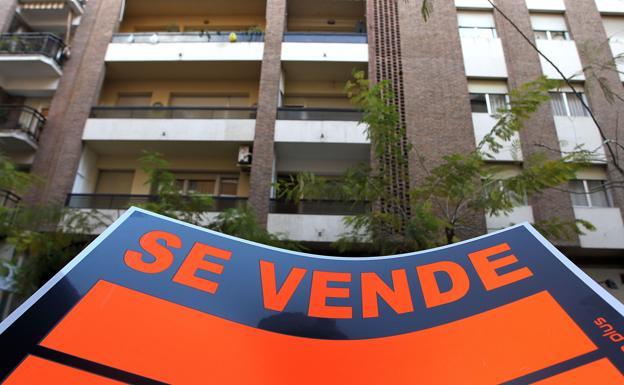 Un cartel de se vende ante varias viviendas. 