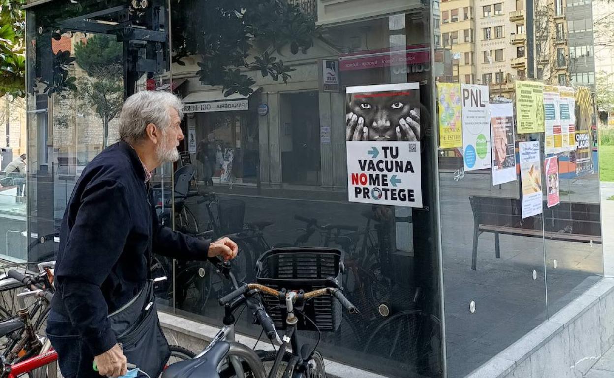 Un hombre observa el cartel colocado por la Plataforma Pobreza Cero en Donostia.