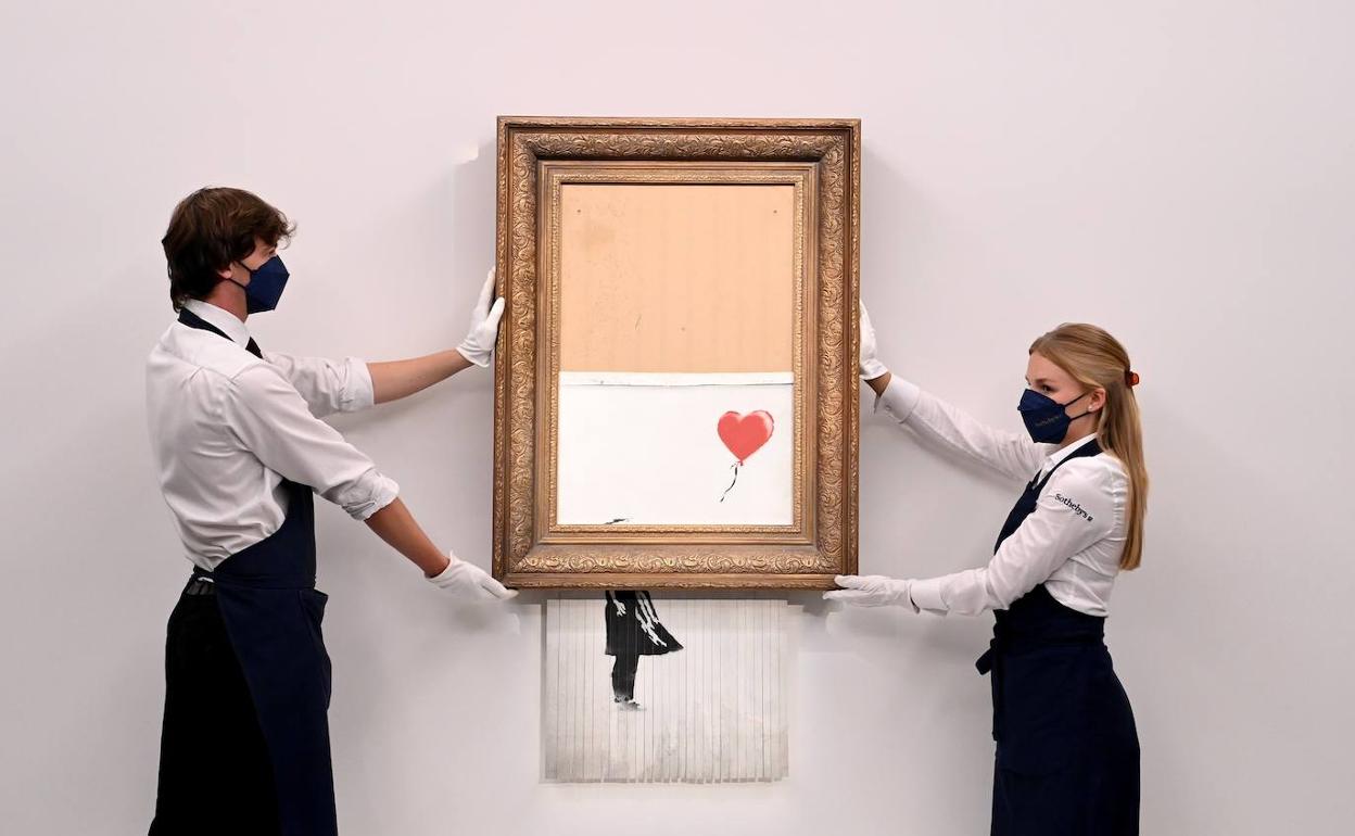 Empleados de Sotheby's muestran la obra de Banksy