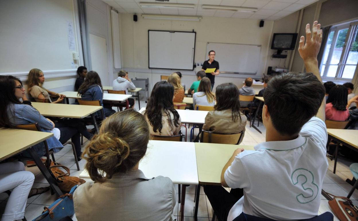 Un alumno levanta la mano para participar en clase, en una imagen de archivo de antes de la pandemia. 