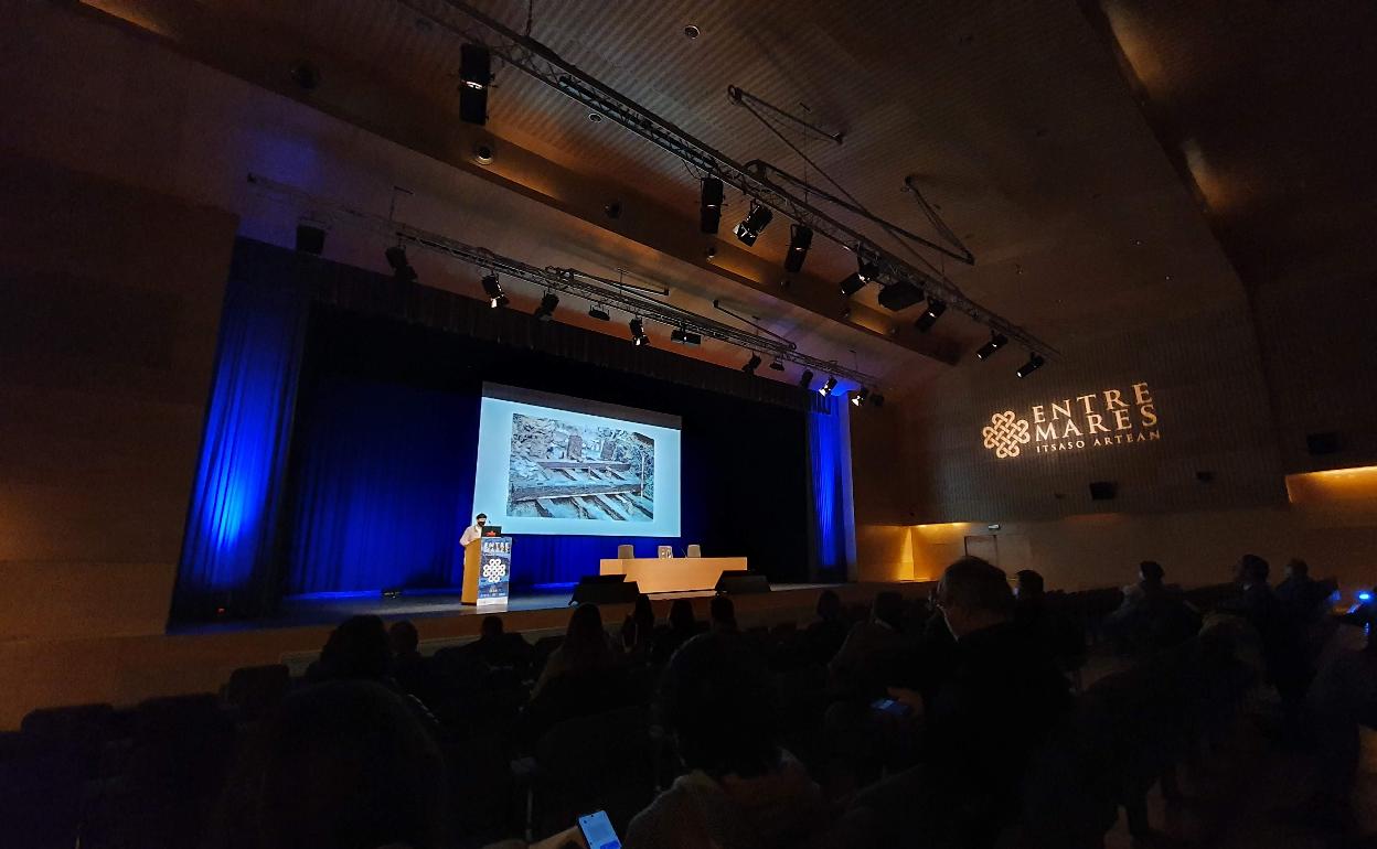 Intervención de Mertxe Urteaga en Entre Mares con una imagen de los restos del puerto de Oiasso de fondo. 