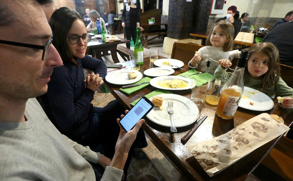 Una famiilia madrileña enseña su certificado de vacunación en una sidrería de Astigarraga, una de las localidades en rojo. 