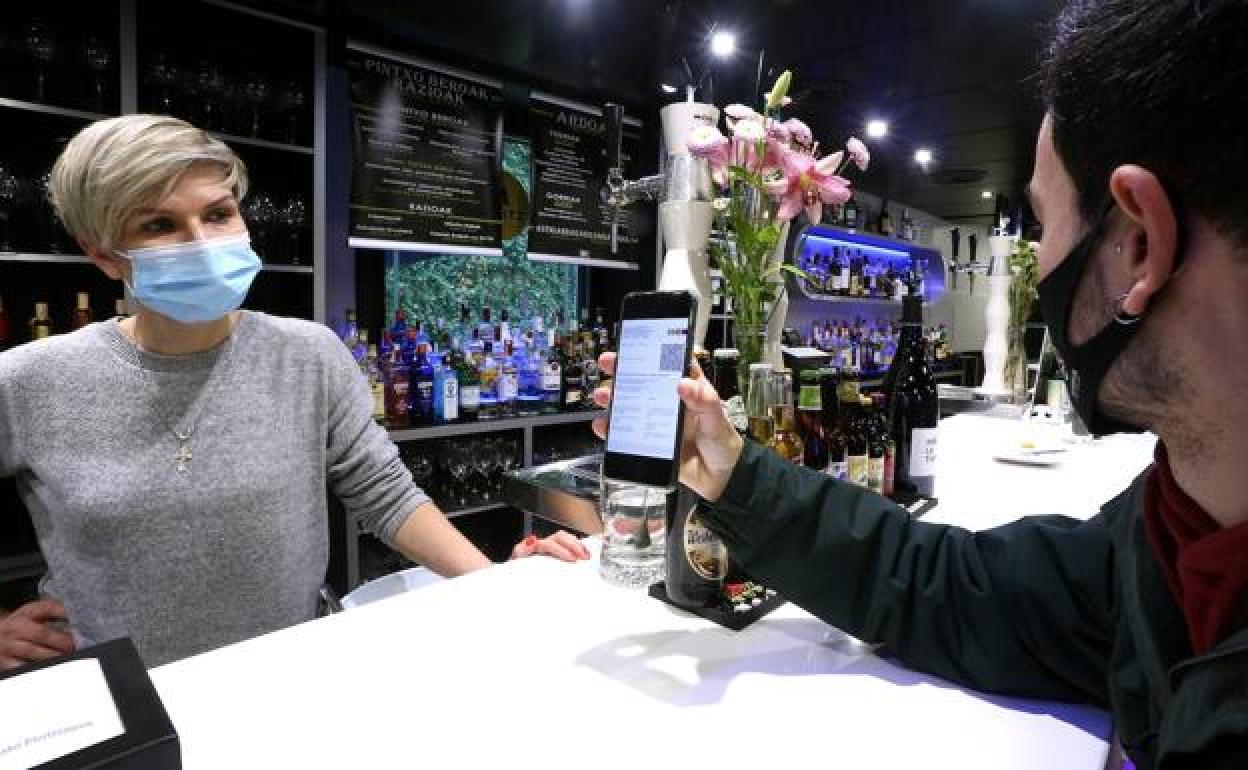Un cliente enseña su pasaporte Covid en un bar de Astigarraga.