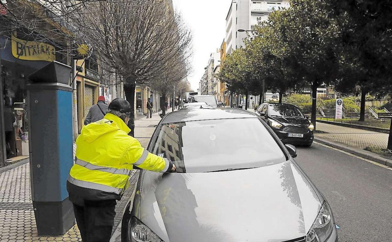 Un agente de la OTA coloca una multa en el parabrisas de un vehículo estacionado en el barrio de Egia. 