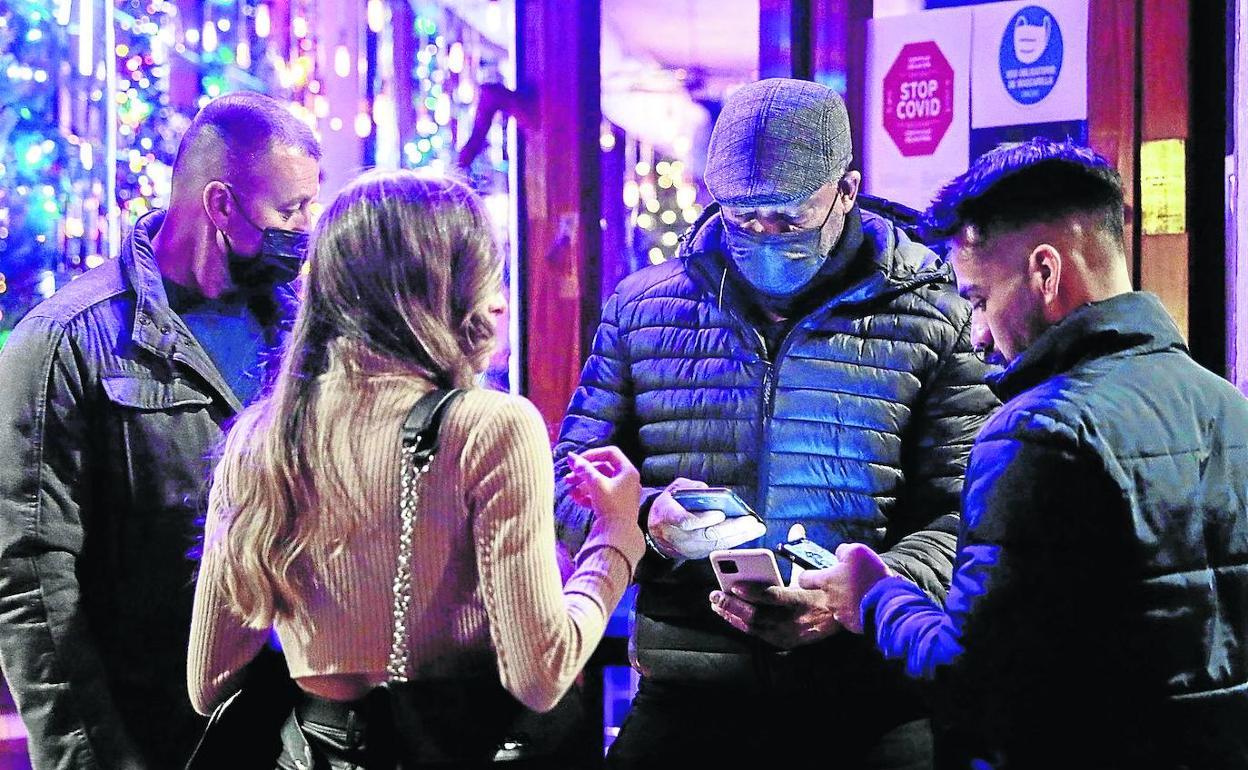 Un vigilante de seguridad chequea el pasaporte Covid a dos clientes en Valencia. 