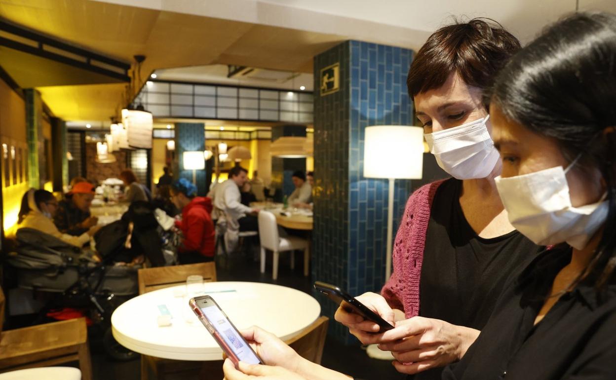 Jatetxe bateko arduraduna agiria egiaztatzen. Atzealdean, musukorik gabeko bezeroak. 