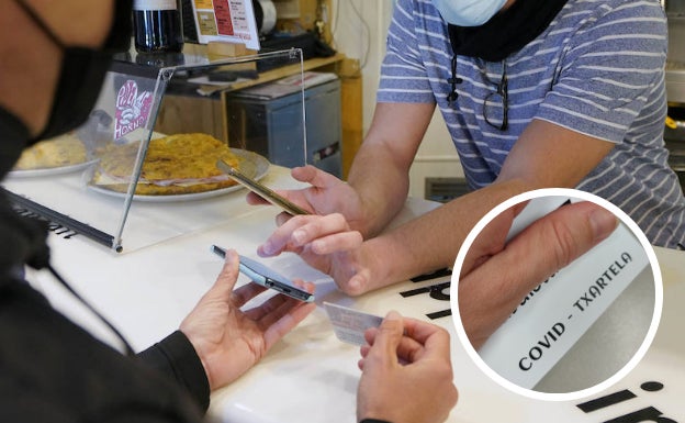 Un hostelero pide el pasaporte Covid a una clienta. En detalle, una Covid txartela que algunos hosteleros están repartiendo ya entre sus clientes habituales