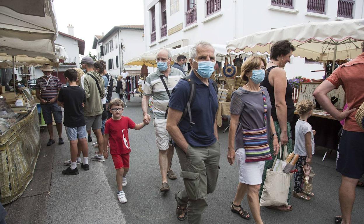 Ciudadanos con mascarilla pasean por el centro de Hendaia.