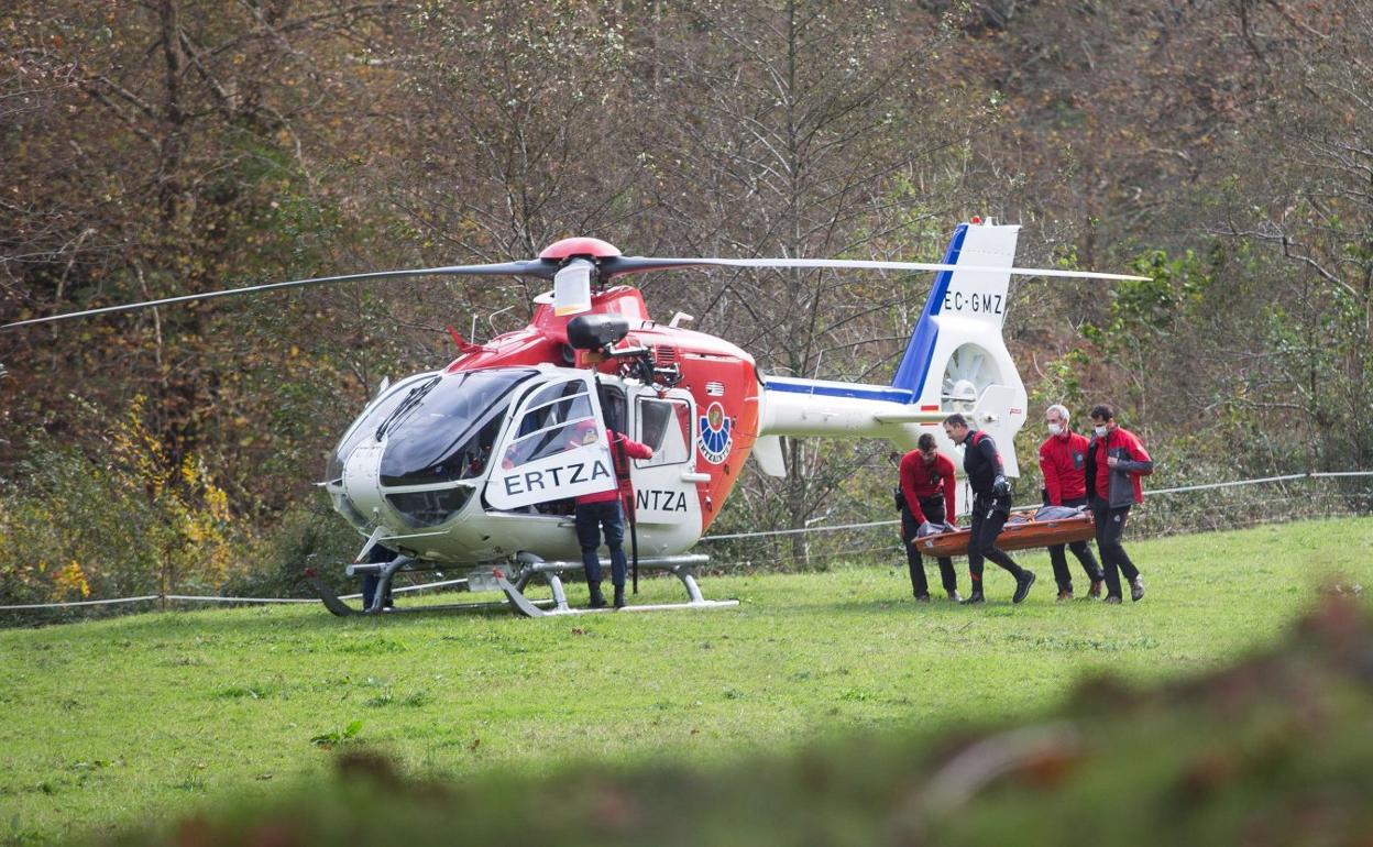 Arriba, varios ertzainas trasladan el cuerpo del migrante muerto en el Bidasoa en noviembre. 