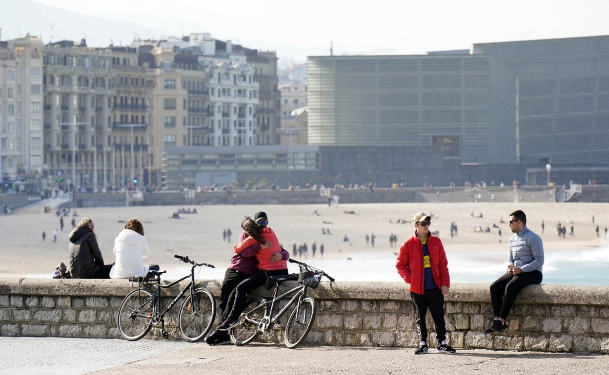 Varias personas disfrutan de la mañana soleada de ayer en el muro de Sagüés, con la playa de la Zurriola de fondo. 