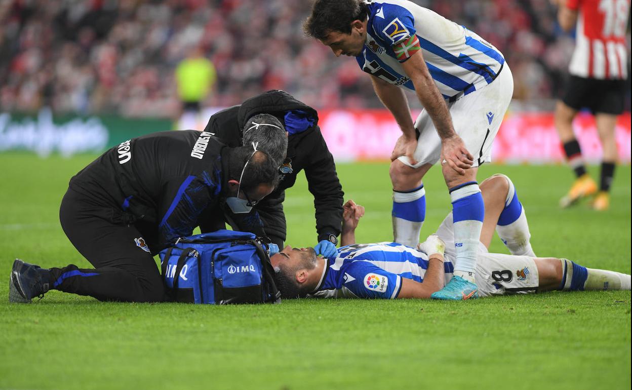 Mikel Merino es atendido por Imanol Soroa y Javier Barrera en San Mamés ante la presencia de Mikel Oyarzabal. 