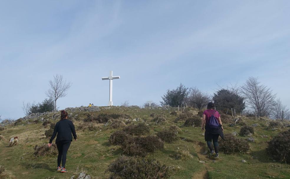 Dos personas se dirigen hacia la gran cruz de Pagoeta.