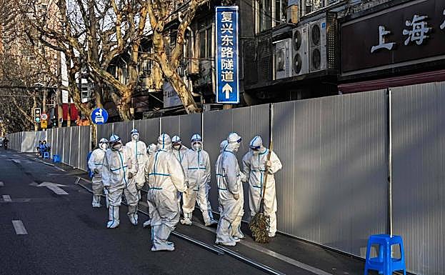Trabajadores en Shanghai (China) en labores de limpieza junto a un barrio confinado por el Covid-19. 