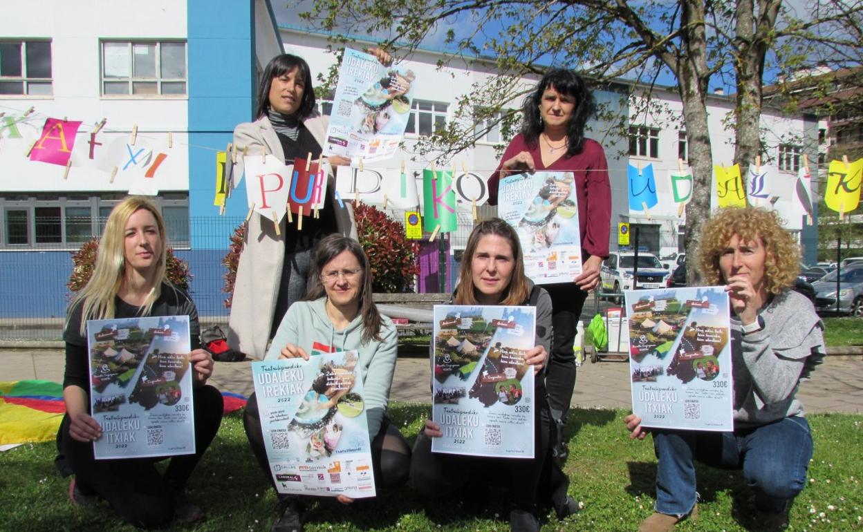 Txatxilipurdiko arduradun eta langileak udalekuak iragartzeko egindako kartela erakusten Nafarroa etorbideko egoitzaren aurrean. 