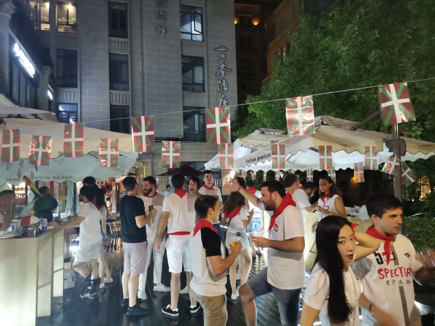 Jóvenes vascos y chinos, ataviados con el pañuelo rojo 'sanferminero', durante una fiesta en la calle. 