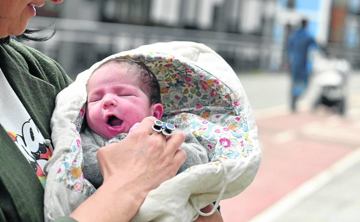 Una madre hace una carantoña a su bebé recién nacido en una calle de Eibar. 