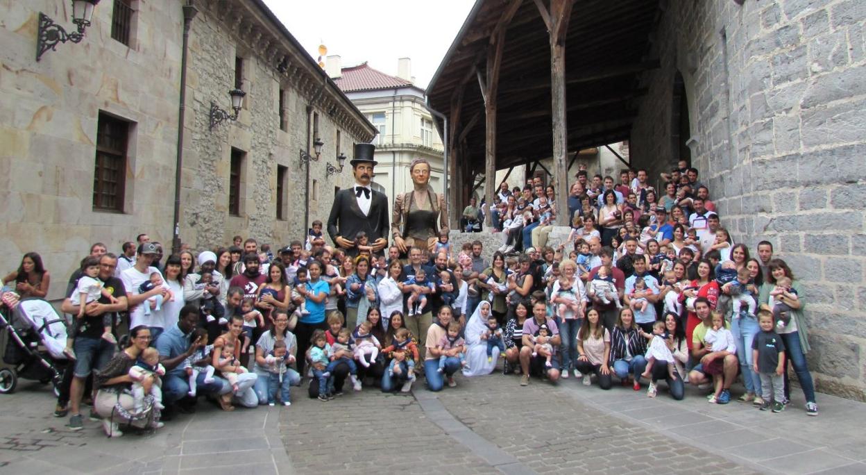 Padres y abuelos se sumaron a la fiesta de recibimiento a los y las 103 bebés nacidos desde los pasados Pentekostes que tras recibir el pañuelo mahón posaron junto a los gigantes Elegantes de la comparsa local. 