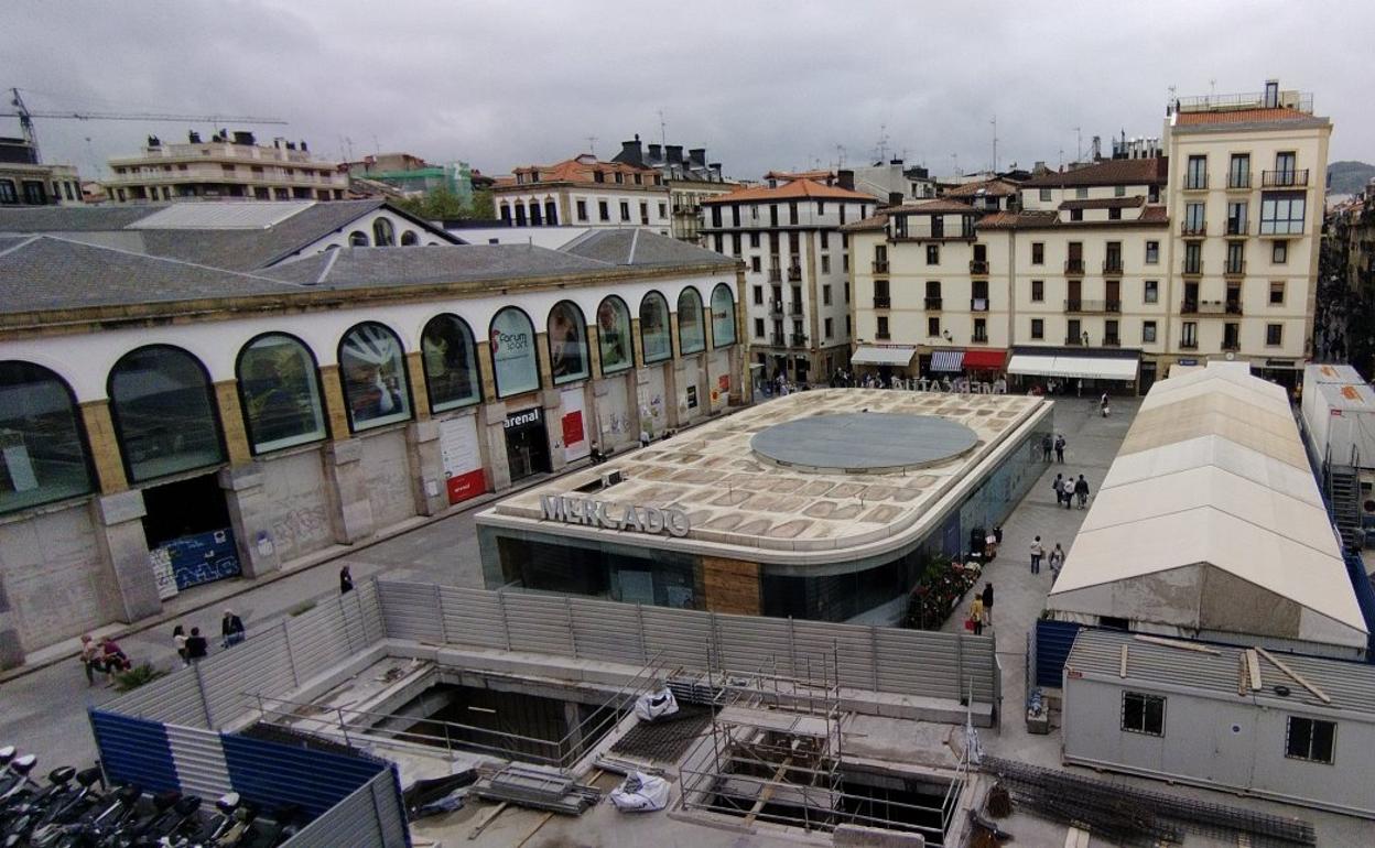 En la parte inferior, obras para construir el nuevo acceso a la planta sótano. En el centro de la plaza, el 'túper' que desaparecerá. Las caseras se trasladarán a la fachada con arcos de la izquierda. 