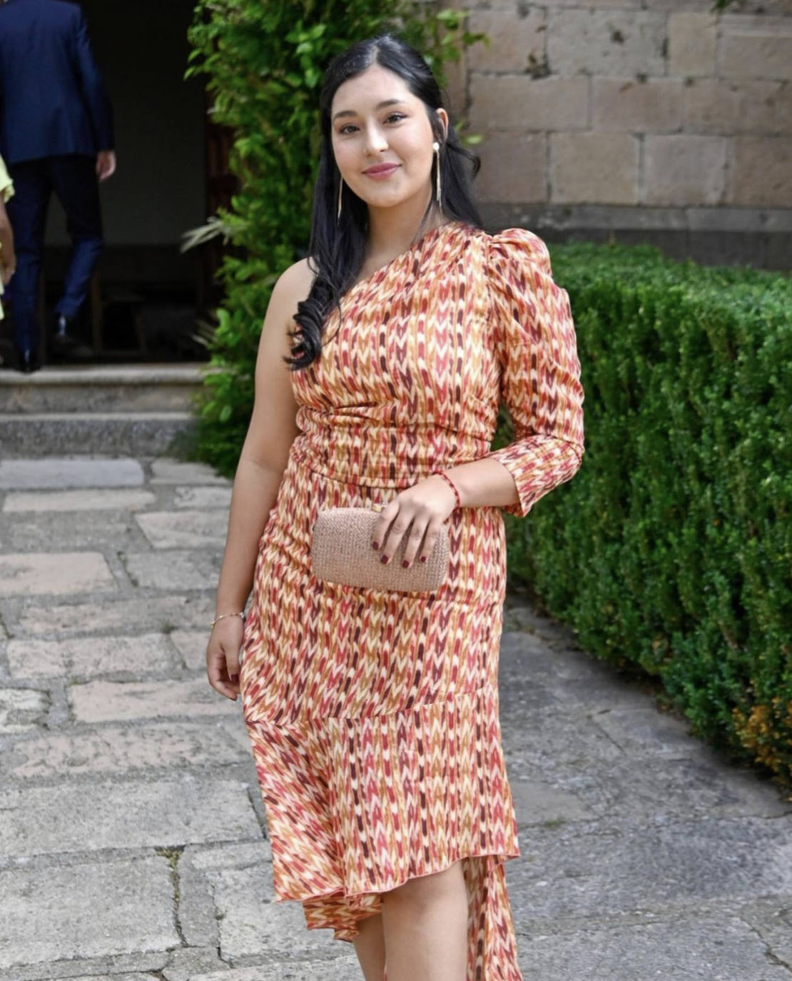 Gabriela Toral, la denominada "cuarta" hermana Pombo, se ha enfundado un modelo 'midi' de estampado étnico con predominio del rojo, naranja, beige y morado; con corte asimétrico y manga abullonada. Ha rematado el estilismo con un 'clutch' rosa empolvado, sandalias de tiras amarillas y un juvenil semirecogido