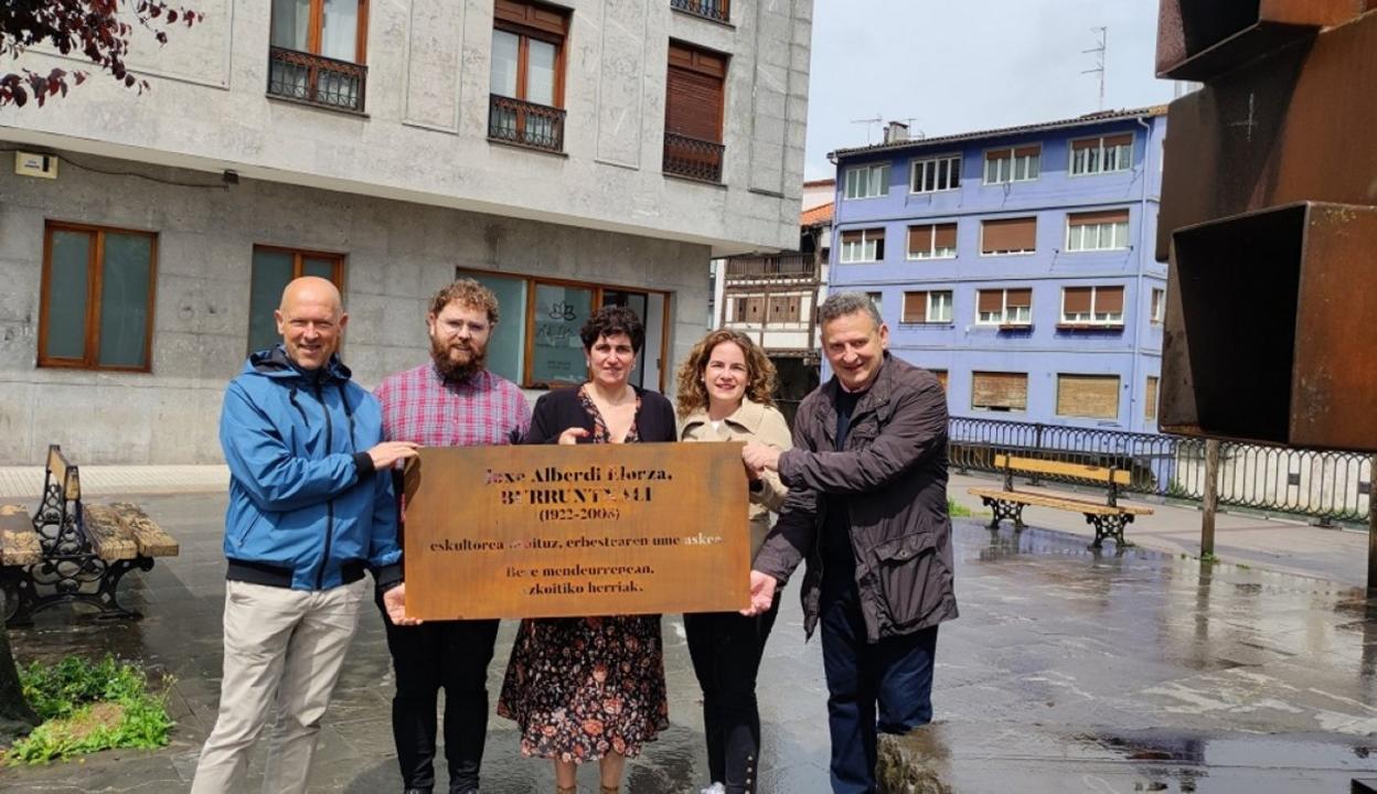 Representantes de todos los aprtidos políticos de Azkoitia sostienen la placa en honor al escultor. 